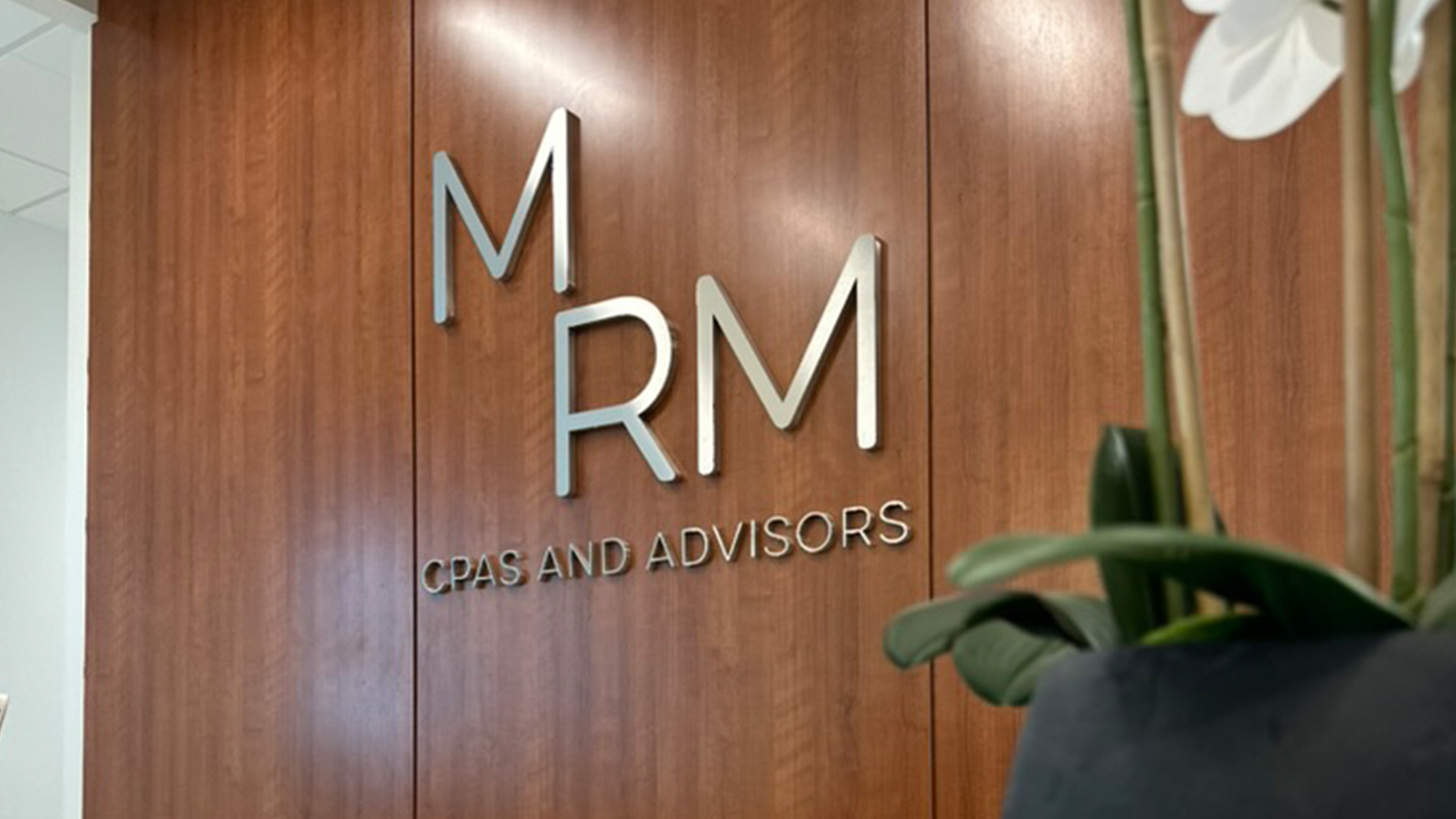 Entrance to the MRM office featuring a metal sign of the logo on a wood backdrop